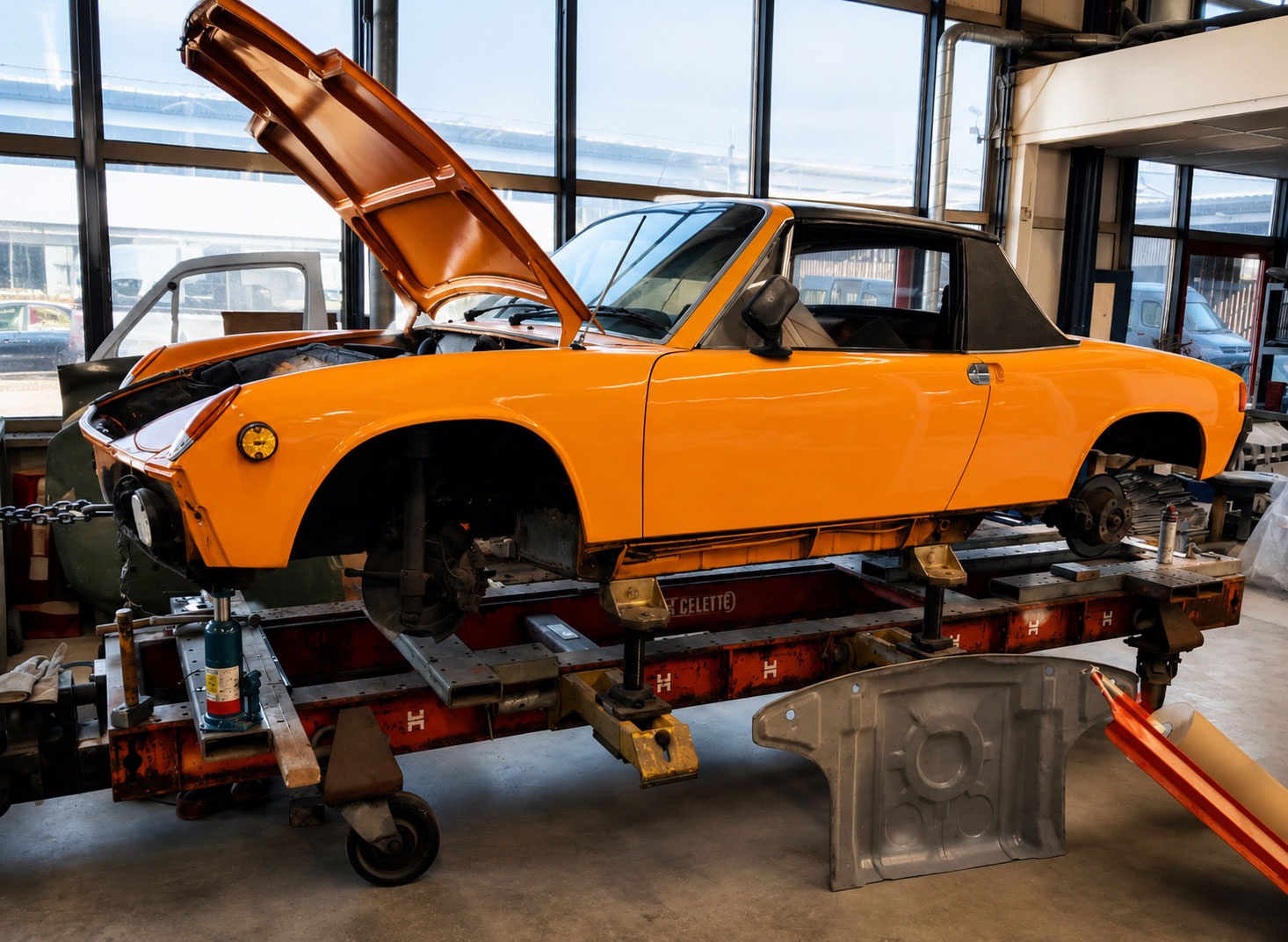 Alt-tekst Oranje Porsche 914 tijdens de eerste inspectie van de carrosserie in de werkplaats van Vallei Classics